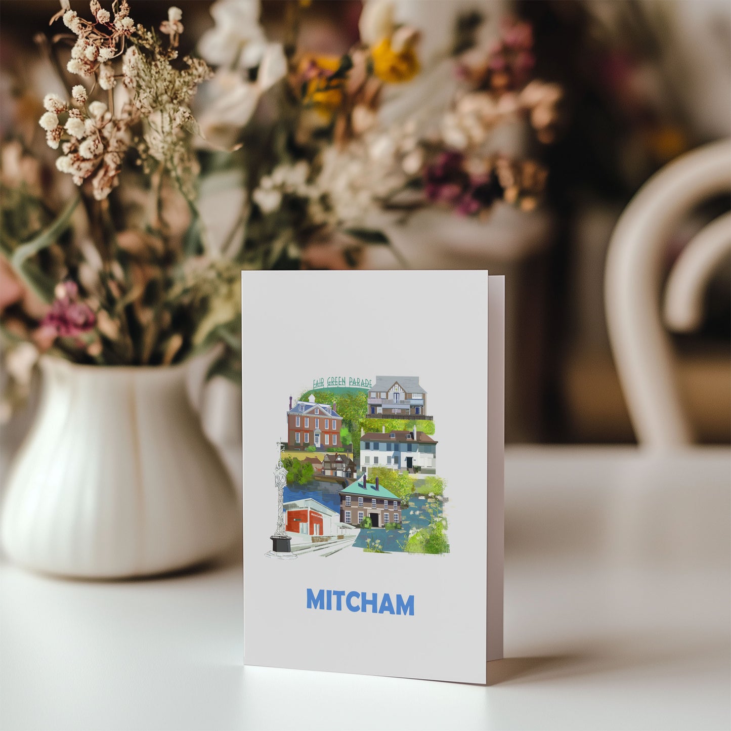 Mitcham greeting card on table with bunch of flowers behind