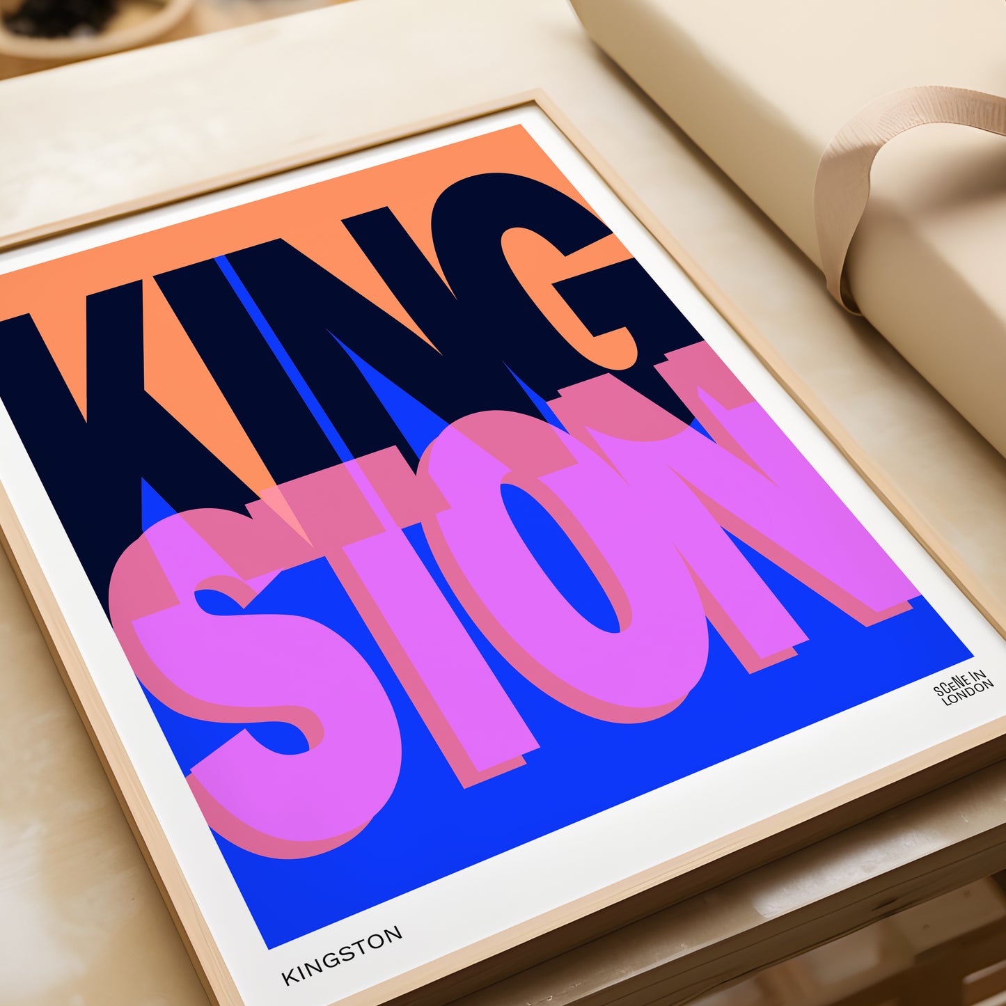 Framed poster with colourful text 'KINGSTON' on a light wooden surface.